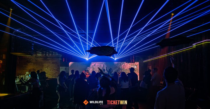 A fan of blue lasers spreading out over the crowd from the back of the room