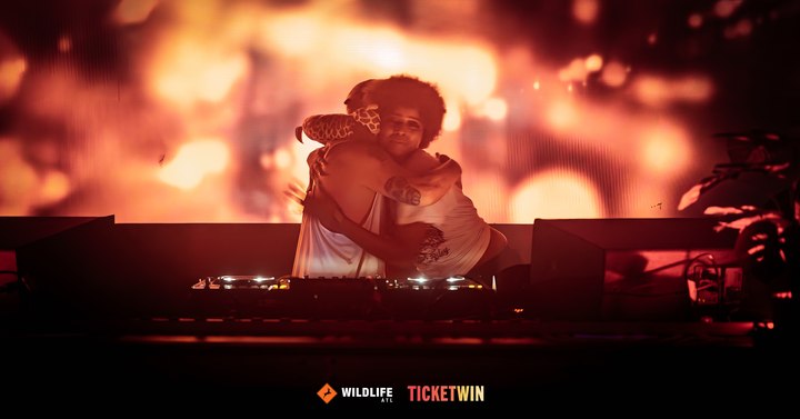 A DJ silhouetted against a wall-sized red projection of their own performance